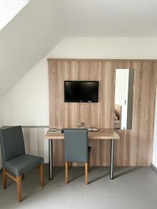 a desk with two chairs and a television on a wall at Hotel Garni Illertal in Altenstadt +8 photos