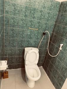 een badkamer met een toilet in een groene betegelde muur bij Sanaa Hostel in Zanzibar City