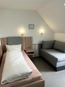 アルテンシュタットにあるHotel Garni Illertalの小さなベッドルーム(ベッド1台、ソファ付)