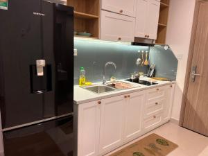 eine Küche mit einer Spüle und einem schwarzen Kühlschrank in der Unterkunft Vinhome Grand Park Homestay House-Romantic Stay in Gò Công