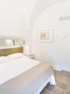 ein weißes Schlafzimmer mit einem Bett und einem Waschbecken in der Unterkunft Masseria Alchimia in Fasano