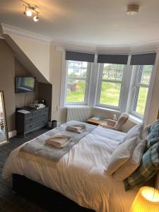 a bedroom with a large bed and two windows at No 4 Portpatrick B&B in Portpatrick