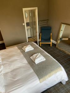 a bedroom with a bed with a mirror and a blue chair at No 4 Portpatrick B&B in Portpatrick
