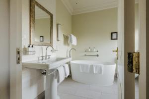 a white bathroom with a tub and a sink at Victoria in Holkham