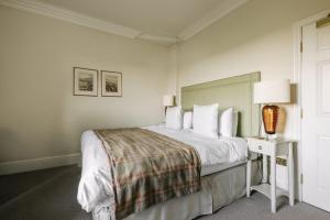 a white bedroom with a bed and a table with a lamp at Victoria in Holkham