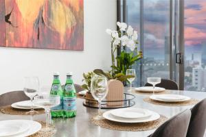 - une table à manger avec des assiettes et des bouteilles de vin dans l'établissement Multi Million River View 3BD Penthouse at SouthBank, à Brisbane