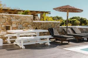 a patio with a white table and chairs and an umbrella at Mykonian Atmosphere in Kalo Livadi