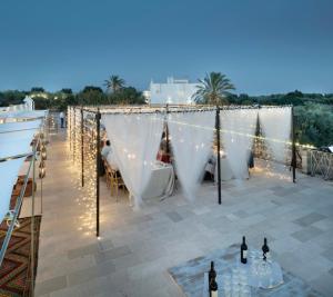 - une terrasse avec un chapiteau, des bouteilles de vin et des lumières dans l'établissement Masseria Alchimia, à Fasano