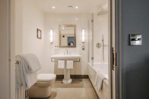 a white bathroom with a sink and a toilet at Victoria in Holkham