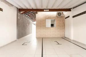 an empty room with a brick wall and white tile floor at Pousada Casa da Fernanda, Suíte Moon in Praia Grande