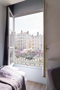 a bedroom with a window with a view of a city at Hotel du Théatre in Lyon
