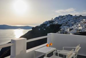 a balcony with white chairs and a view of the ocean at Aeifos Boutique Hotel in Imerovigli