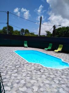 a swimming pool with two green chairs and a fence at Maison charmante proche de la plage au Moule avec piscine in Le Moule