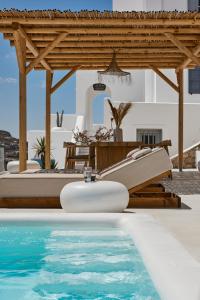 a pool with a wooden pergola and a table and a swimming pool at Bluewhite Villa Santorini in Pirgos