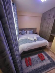 a bedroom with a bed with two red shoes on it at Blue House 2 Bedroom House. in Naivasha