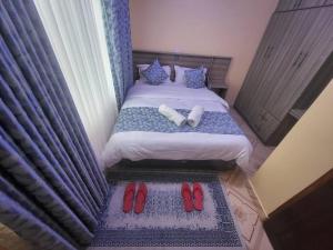 a bedroom with a bed with red shoes on it at Blue House 2 Bedroom House. in Naivasha