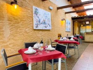 un restaurante con mesas rojas y sillas con copas de vino en Hostal Ainoa, en Berlanga de Duero