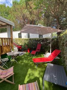 a patio with a table and chairs and an umbrella at Charmant mobil home 331 camping 4* Siblu La Réserve in Gastes