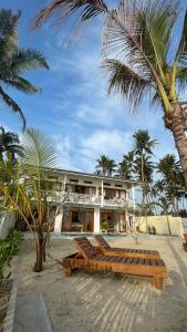 a house on the beach with a bench and palm trees at Lihinya Beach Villa Ahangama in Ahangama
