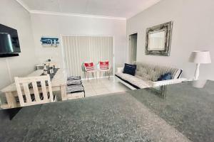 a living room with a couch and a table and chairs at Stylish Hartenbos Apartment in Mossel Bay