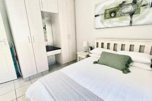 a bedroom with a white bed with a green pillow at Stylish Hartenbos Apartment in Mossel Bay