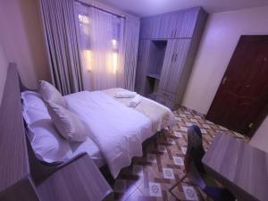 a bedroom with a bed with white sheets and pillows at Zambezi House. 2 bedroom apartment in Naivasha +1 photo