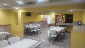 un restaurante con mesas y sillas blancas y paredes amarillas en Hotel POSADA DEL REY en Matamoros