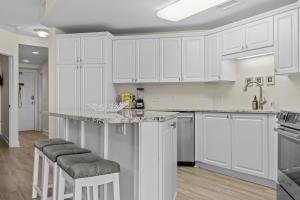 una cocina blanca con armarios blancos y taburetes de bar en Yacht Club Dream condo, en Beaufort