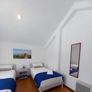 een witte kamer met 2 bedden en een spiegel bij Vista do Canal Plus in Horta