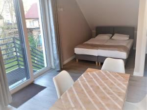 a bedroom with a bed and a table and a balcony at Apartament nad jeziorem WELLE in Kołczewo