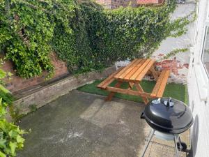 a grill and a wooden picnic table in a backyard at Cosy Home in Historical Beverley Town with Parking in Beverley