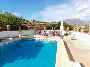 a swimming pool with blue water in front of a house at Casa LIMA in Viñuela