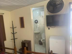 a bathroom with a toilet and a television on the wall at Pousada Boa Noite in Atibaia