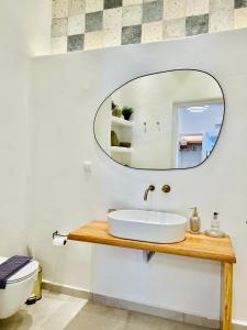 La salle de bains est pourvue d'un lavabo et d'un miroir. dans l'établissement Gerani Deluxe Houses, à Astypalée