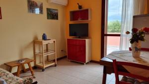 un salon avec une télévision sur un meuble rouge dans l'établissement La casa delle rose, à Su Forti