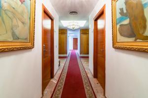 einen Flur mit Gemälden an den Wänden und einem roten Teppich in der Unterkunft Hotel Riad Arruzafa in Córdoba
