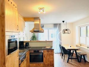 a kitchen with wooden cabinets and a table with chairs at Ferienwohnungen Klose in Gosau