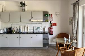 a kitchen with white cabinets and a table at 233 Casa Galo Verde Apartments in Porches