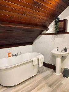 a bathroom with a white tub and a sink at Church Heights by Flying Stays in Pontypool