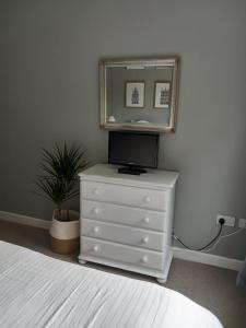 a bedroom with a dresser with a tv and a mirror at Atlantic Shore B&B in Bantry