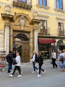 un groupe de personnes marchant devant un bâtiment dans l'établissement Pia's Home in pieno centro storico, à Palerme