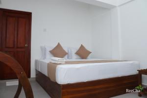 a bedroom with a bed with white sheets and pillows at Reecha Organic Resort Jaffna in Kilinochchi