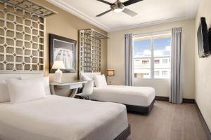 1 dormitorio con 2 camas, escritorio y ventana en Waldorf Towers South Beach en Miami Beach