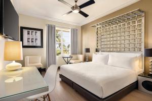 a bedroom with a large white bed and a desk at Waldorf Towers South Beach in Miami Beach