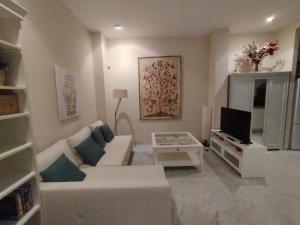 a living room with a white couch and a tv at Alleanza, Suite Cathedral, Private Rooftop in Seville