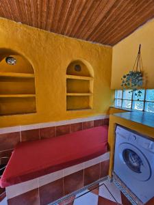 a laundry room with a red bench and a washing machine at Labriega del hueznar in Cazalla de la Sierra