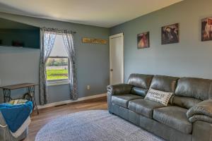 a living room with a leather couch and a window at Upstate New York Vacation Rental Near Cooperstown! in Cherry Valley