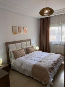 sypialnia z dużym łóżkiem i dużym oknem w obiekcie Appart calme & chaleureux en résidence près de la mer w mieście Monastir