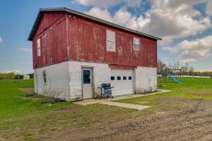 a red and white barn with a grill in a field at Upstate New York Vacation Rental Near Cooperstown! in Cherry Valley