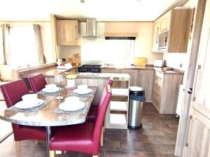 a kitchen with a table and red chairs in a kitchen at Sand Le Mere Holiday Village Caravan hire in Tunstall